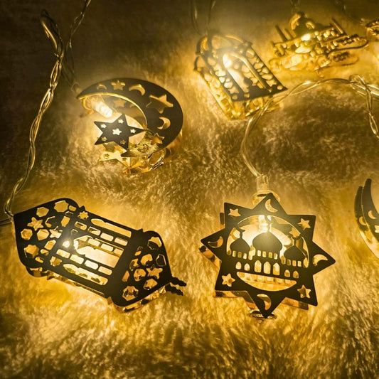 Close-up of golden Ramadan and Eid metal string lights with crescent moon, mosque, and lantern designs glowing warmly by Islamify