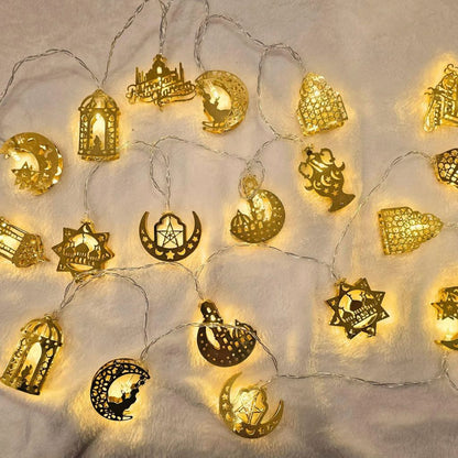 Golden Ramadan and Eid string lights featuring lanterns, mosques, crescents, and stars glowing warmly on a soft surface by Islamify