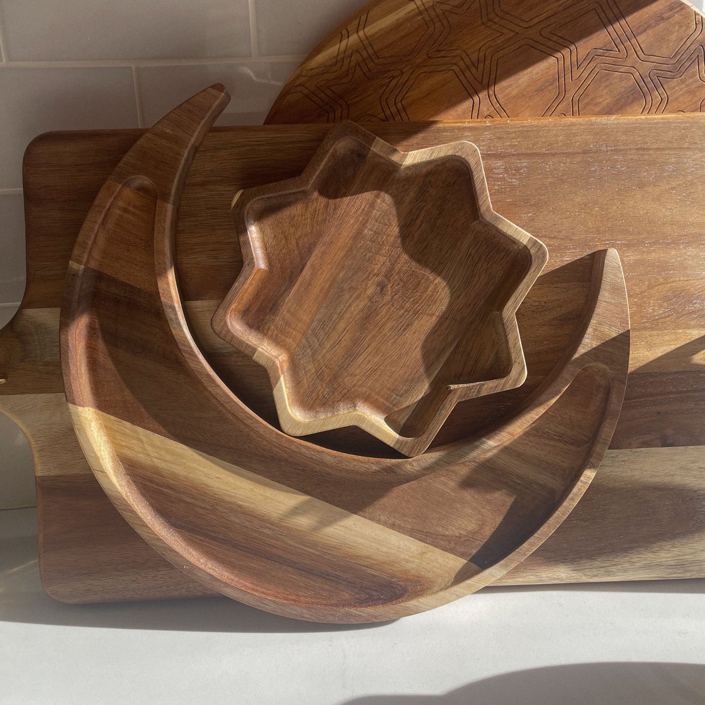 Wooden crescent moon and star-shaped plates displayed in natural light on a wooden surface – Ramadan and Eid serveware by Islamify